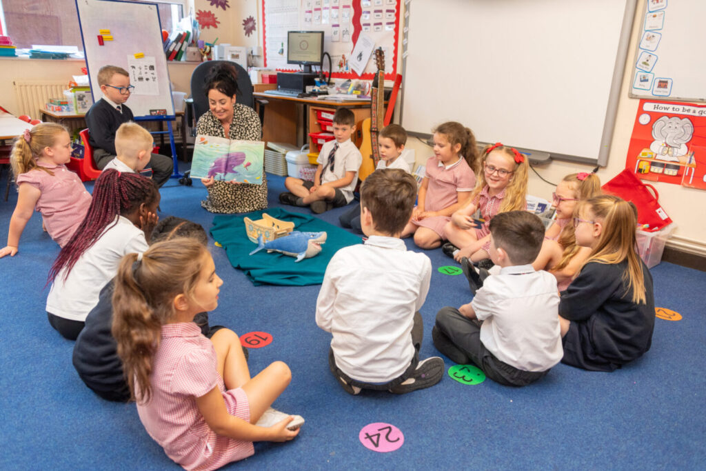 a picture of a teacher showing the class a book